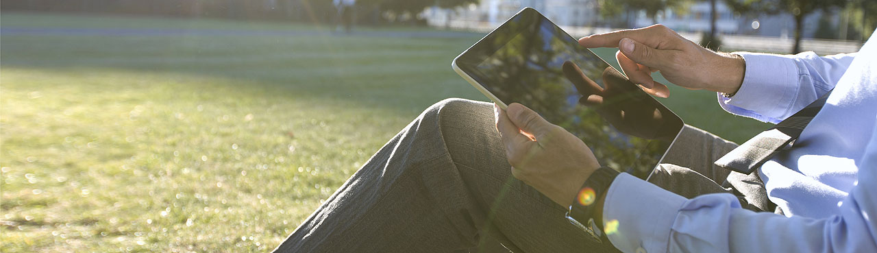 Man zit in het gras en bekijkt tablet